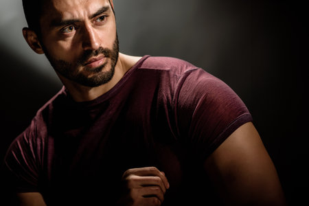 Beauty portrait of handsome bearded muscular man posing in studio, A dark and dramatic portrait of a strong man exuding a brutal charisma with a commanding beardの写真素材