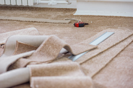 New brown carpet and tools for installation lying on floor. Detailed view of carpet cutting, highlighting the care and skill involved in fitting flooringの写真素材