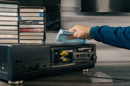 Closeup of man cleaning dust from his retro audio tape recorder. Clean and organized listening room...