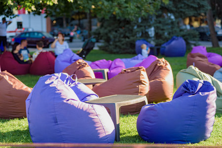 Many colorful bean bags chairs in park on green lawn. Soft chairs on the grass offer relaxation and rest, perfect for a weekend getaway in the cityの写真素材