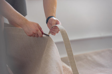 Closeup photo of male hands cutting carpet with blade. Close-up of a man cutting carpet during a repair, emphasizing professional craftsmanshipの写真素材