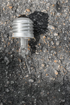 Closeup photo of damaged incandescent light bulb on asphalt, Broken incandescent bulb with visible...