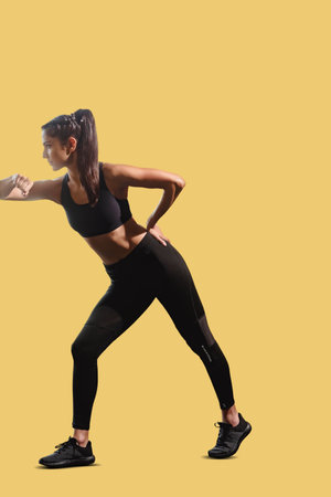 Active fit young girl stretching her body on yellow background, Isolated girl in fitness gear on a...