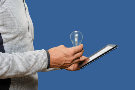 Closeup photo of male electrician checking indications of incandescent lamp on tabletの写真素材