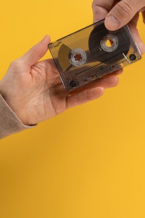 Female hand giving vintage magnetic audio tape cassette to male music lover. Hand holding an audio cassette on a clean flat background, ideal for designs emphasizing music nostalgia and retro vibesの写真素材