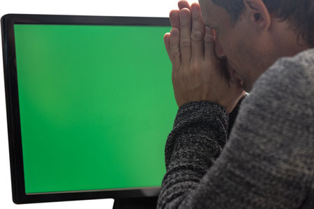 Sad exhausted young man tired of working on computer. Close-up of man gesturing at computer with chroma key screen, isolatedの写真素材