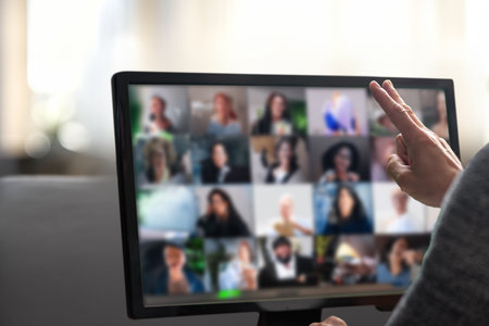 Man talking with diverse colleagues on virtual video conference using computer at home. Man working remotely in a home office, actively communicating during a virtual conference callの写真素材
