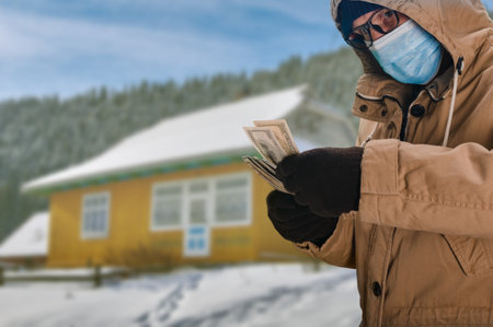 Man in medical mask buying mountain cottage during coronavirus epidemicの写真素材