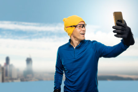 Young smiling male athlete using smartphone for taking selfie while running outdoorの写真素材