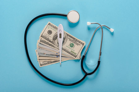 Thermometer, stethoscope and dollars cash money isolated on blue backgroundの写真素材
