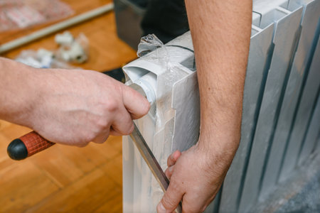 Male plumber installing water heating radiator, closeup photo. Worker unpacking new heating battery, getting ready for installation, home renovation processの写真素材