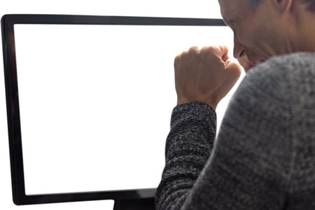 Young man looking at computer screen and feeling confused. Close-up of man at computer, seen from behind, white screen offering copy spaceの写真素材