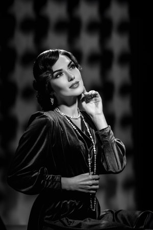 Black and white portrait of attractive glamorous young actress posing in vintage clothes. Elegant girl with retro wave hair in Harcourt-style black and white portrait like classic actressの写真素材
