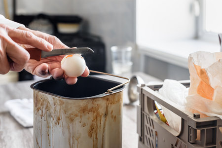 Closeup of man cracking an egg into form to make bread according to traditional recipe. Baking bread at home with sugar, salt, spoon pouring ingredients, and egg in the doughの写真素材