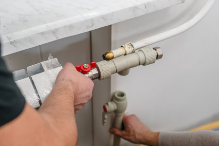 Male plumber connecting radiator after leakage accident, closeup photo. New heating radiator being...