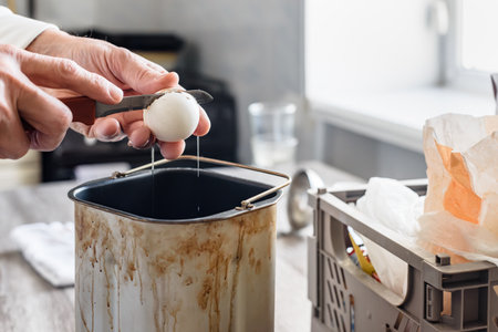 Man cracking raw egg into a bowl in kitchen at home, closeup photo. Preparing dough for baking bread at home with sugar, salt, egg, and spoon pouring ingredientsの写真素材
