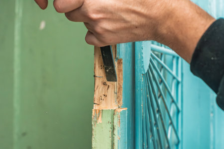 Closeup photo of man working with chisel to install new door lock. Installing door lock, hands shaping wood with chisel for proper hardware fitの写真素材