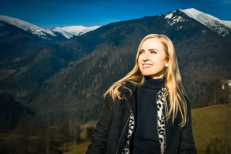 Happy and freedom loving woman enjoying walk in mountains. Female in black jacket enjoying winter...