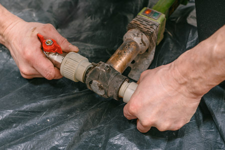 Closeup photo of professional male plumber welding plastic pipe. Plumber cutting and soldering...