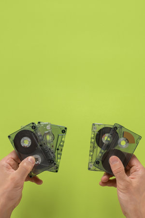 Collection of old retro audio cassettes in hands of male music lover. Retro audio cassette held by...