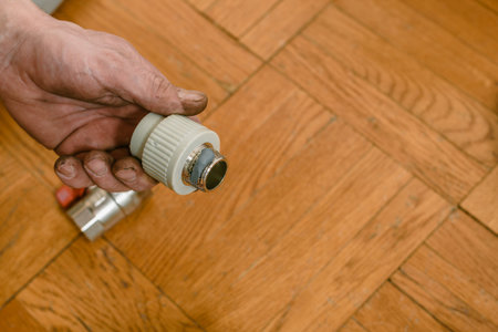 Closeup photo of male plumber holding polypropylene compound for pipes. Plumbing maintenance in...