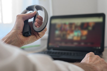 Businessman with expander massaging muscles after computer overwork, closeup photo. Hand grip workout at desk while streaming videos on laptopの写真素材