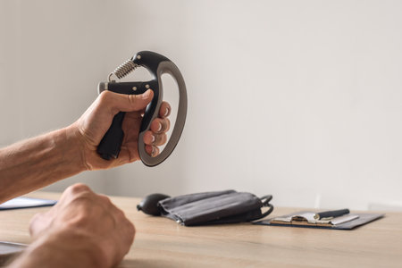 Closeup of man using hand grip strengthener for training his arms. Man training hand muscles with grip strengthener, rehabilitation and therapy conceptの写真素材