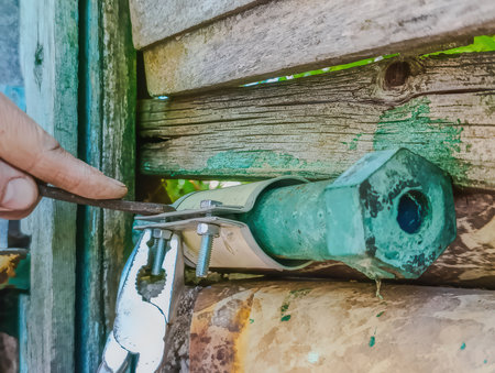 Male plumber with pliers trying to fix old pipe, closeup photo. Securing pipe leak with metal clamp and screwdriver during DIY repairの写真素材
