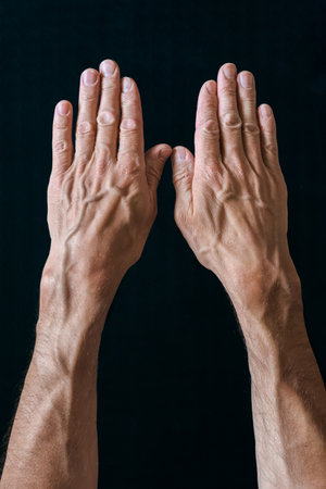 Male hands with blood veins on black background. Veiny male hands, backs up, showing muscle texture, isolated on blackの写真素材