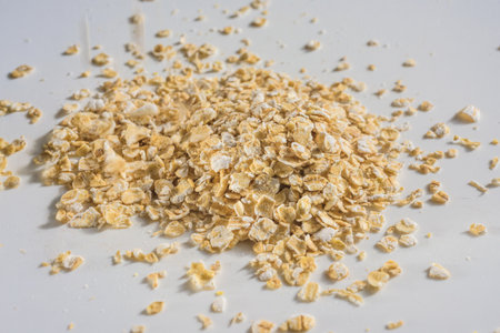 Dry oatmeal flakes on white table, closeup photo. Raw oat flakes scattered on table, healthy breakfast preparation backgroundの写真素材