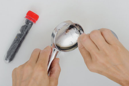 Closeup photo of professional male plumber fixing domestic shower head. Applying glue or sealant to shower head body during repair processの写真素材