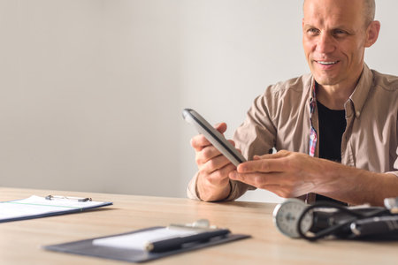 Smiling man exercising with hand gripper in physiotherapy clinics room. Smiling patient holding hand trainer during rehab sessionの写真素材