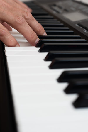 Closeup photo of male hands playing on electronic keyboard. Close-up of hand playing piano keys during casual home music practice.の写真素材