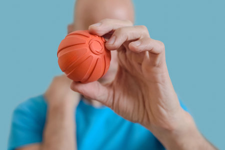 Man showing small ball for massaging stiff muscles and relieve spinal pain. Man holds massage ball for myofascial release and muscle pain relief therapyの写真素材