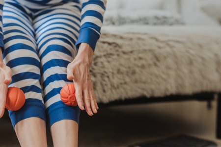 Fitness woman using massage roller ball for myofascial relaxation of muscles. Leg massage with spiky therapy balls in cozy home interiorの写真素材