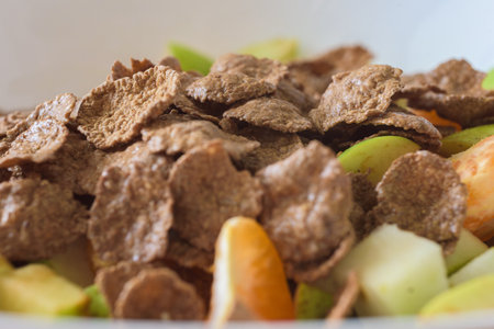 Healthy breakfast with fruit salad and muesli, closeup photo. Bran flakes on top of chopped fruits in bowl, healthy breakfast conceptの写真素材