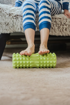Closeup photo of young woman massaging legs with fitness foam roller. Foot massage at home using a textured roller for muscle relaxationの写真素材