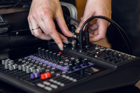 Sound engineer connecting audio cables with music equipment in recording studio Close-up of sound...