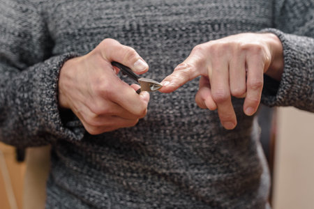 Closeup of man trimming his nails using clippers at home Man trimming fingernails during personal...
