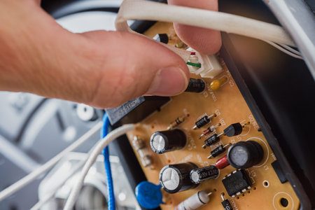 Repairman fixing electric appliance of multicooker, closeup photo. Connecting wires to heating...