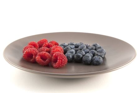 Close up of blueberries and raspberries on a plate. Shallow depth of fieldの写真素材