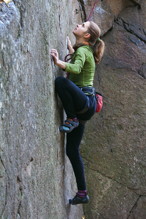 Young girl climbs on a rock. Image of closeup.
