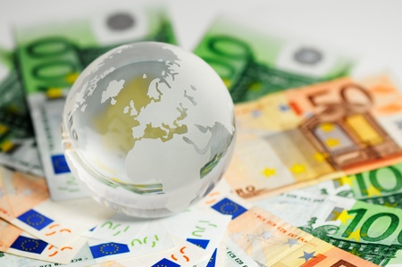 Glass globe and variety of banknotes shot on a white background の写真素材
