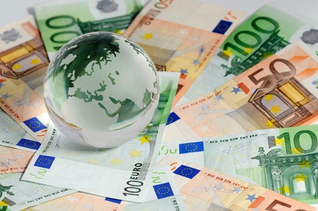 Glass globe and variety of banknotes shot on a white background の写真素材