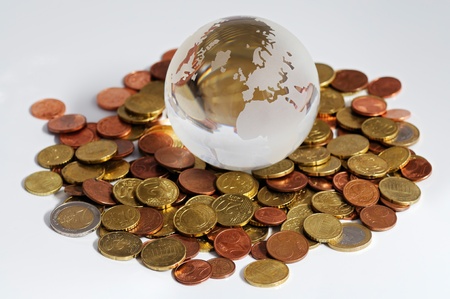Close-up of glass globe and coins shot on a white background の写真素材