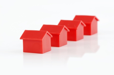Muenster, Germany - April 10, 2010: Row of four red plastic houses from the famous property trading board game Monopoly, isolated on white. Monopoly is owned and manufactured by Hasbro.のeditorial素材