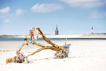 Driftwood with fishing nets logs on beach, Wangerooge, East Frisian Islands, Germanyの写真素材