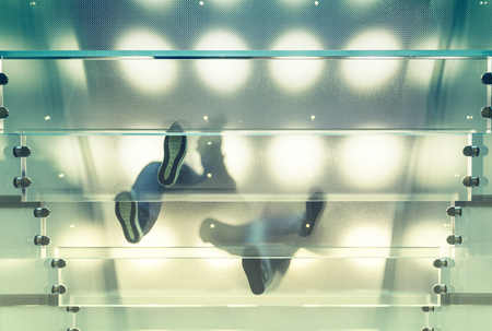 Modern glass staircase with person walking on itの写真素材