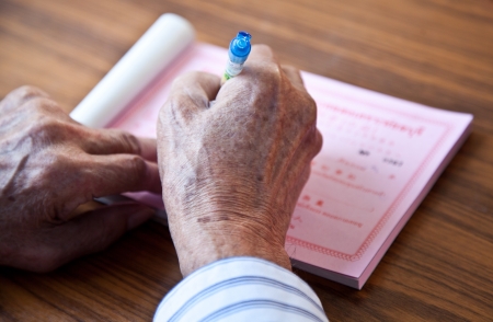 Hands of olderly man writing on deskの写真素材