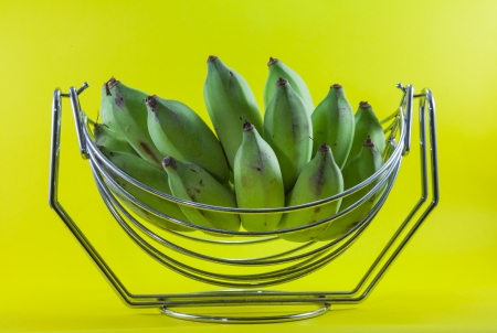 green banana in basket on yellow backgroundの写真素材